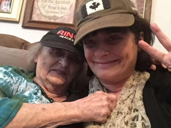 Two women smiling, one elderly and one younger, in a cozy setting