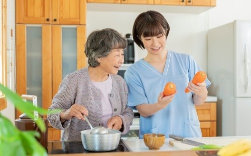 Senior resident and caregiver cooking together