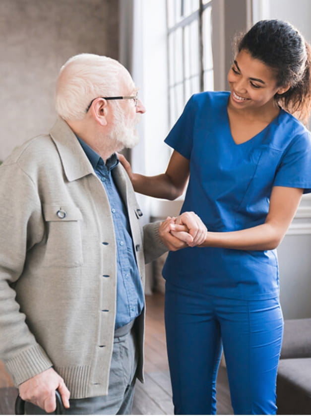 Healthcare worker assisting an elderly man indoors.