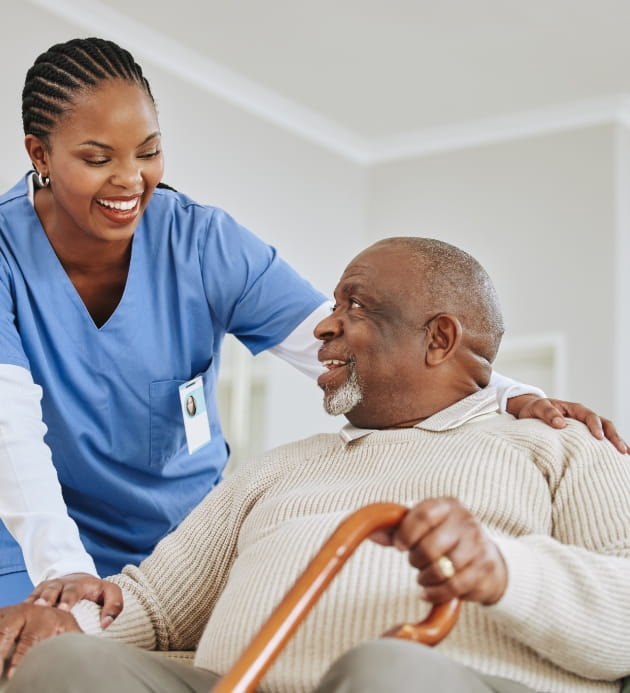 Caregiver assisting an elderly man indoors.