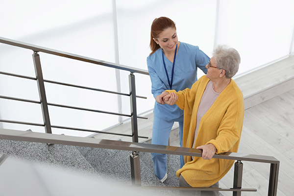 Caregiver assisting a senior woman on stairs