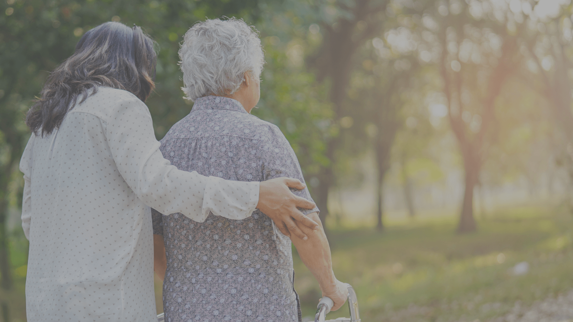 Woman assisting senior with walker in a park