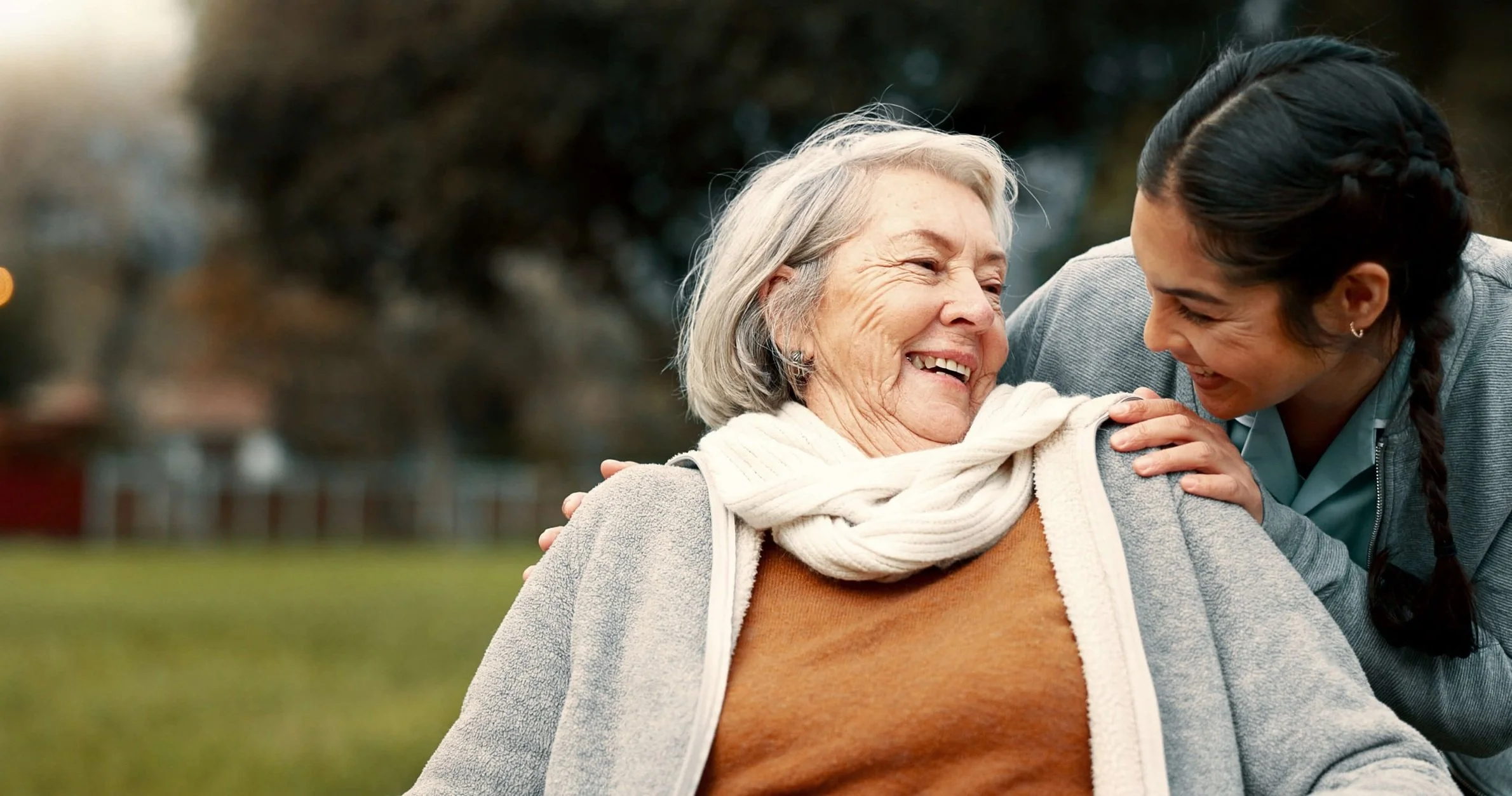 Senior woman laughing with caregiver outdoors