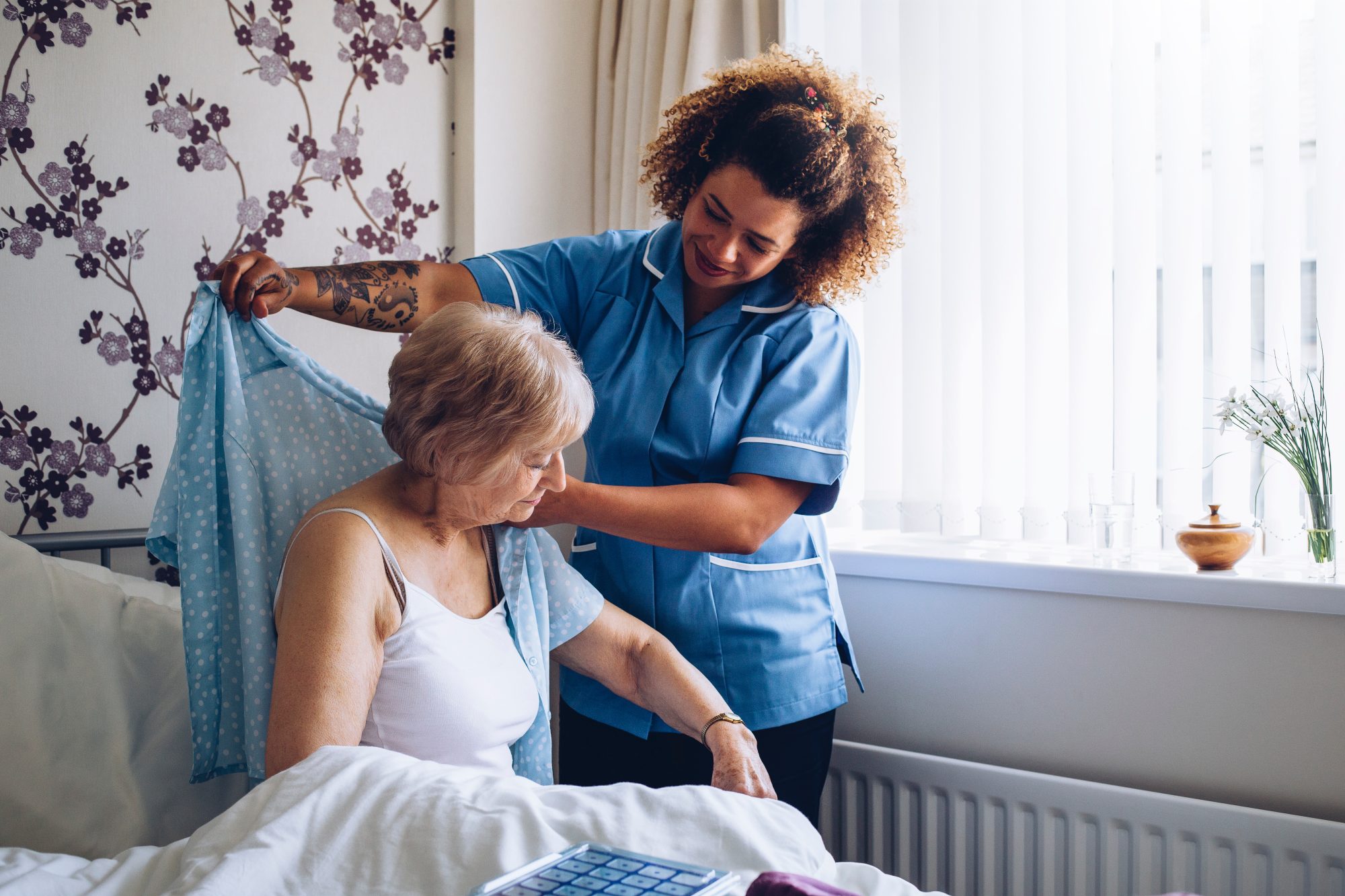 Nurse assisting a resident in a room.