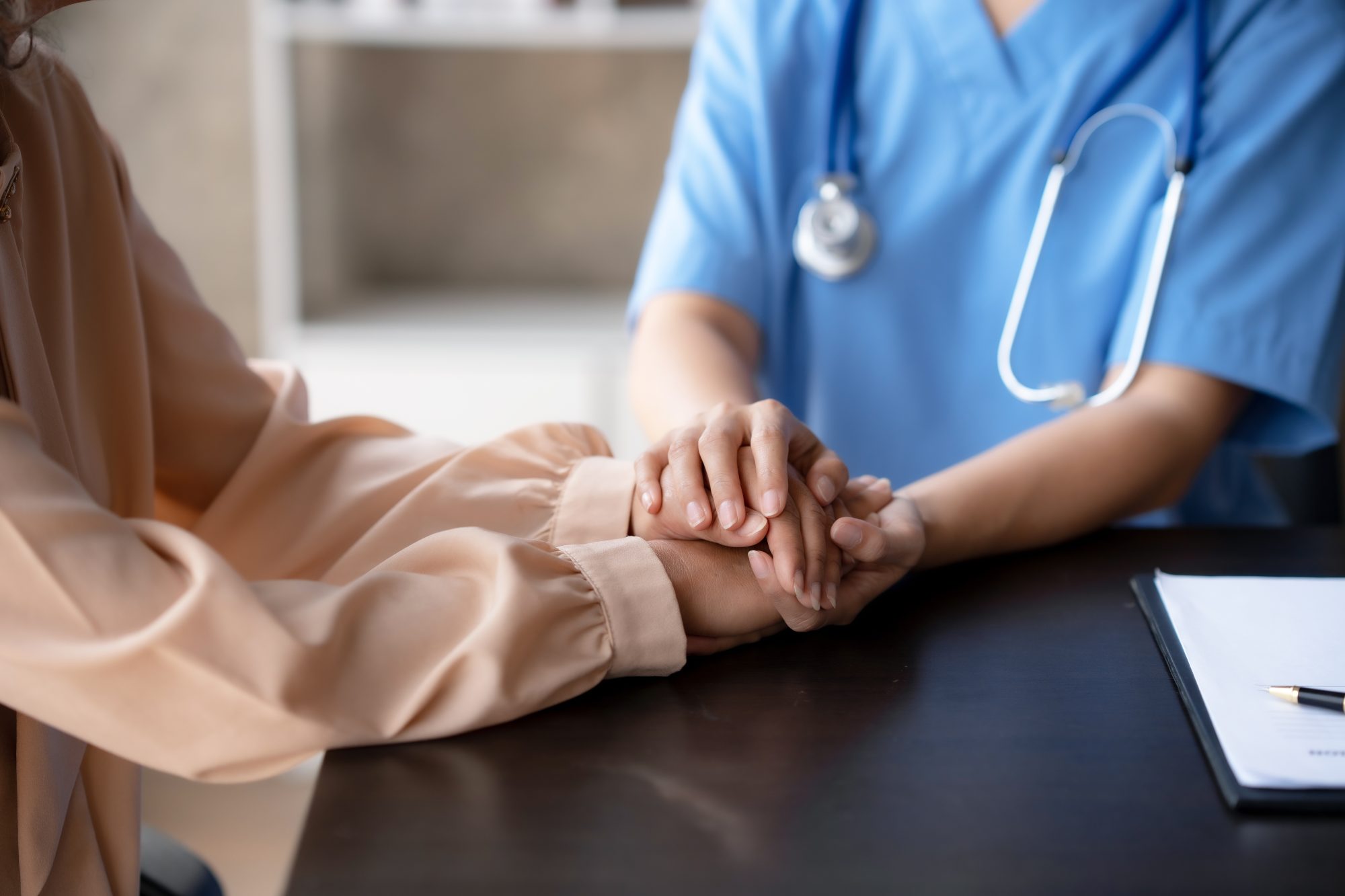 Healthcare professional and patient holding hands.