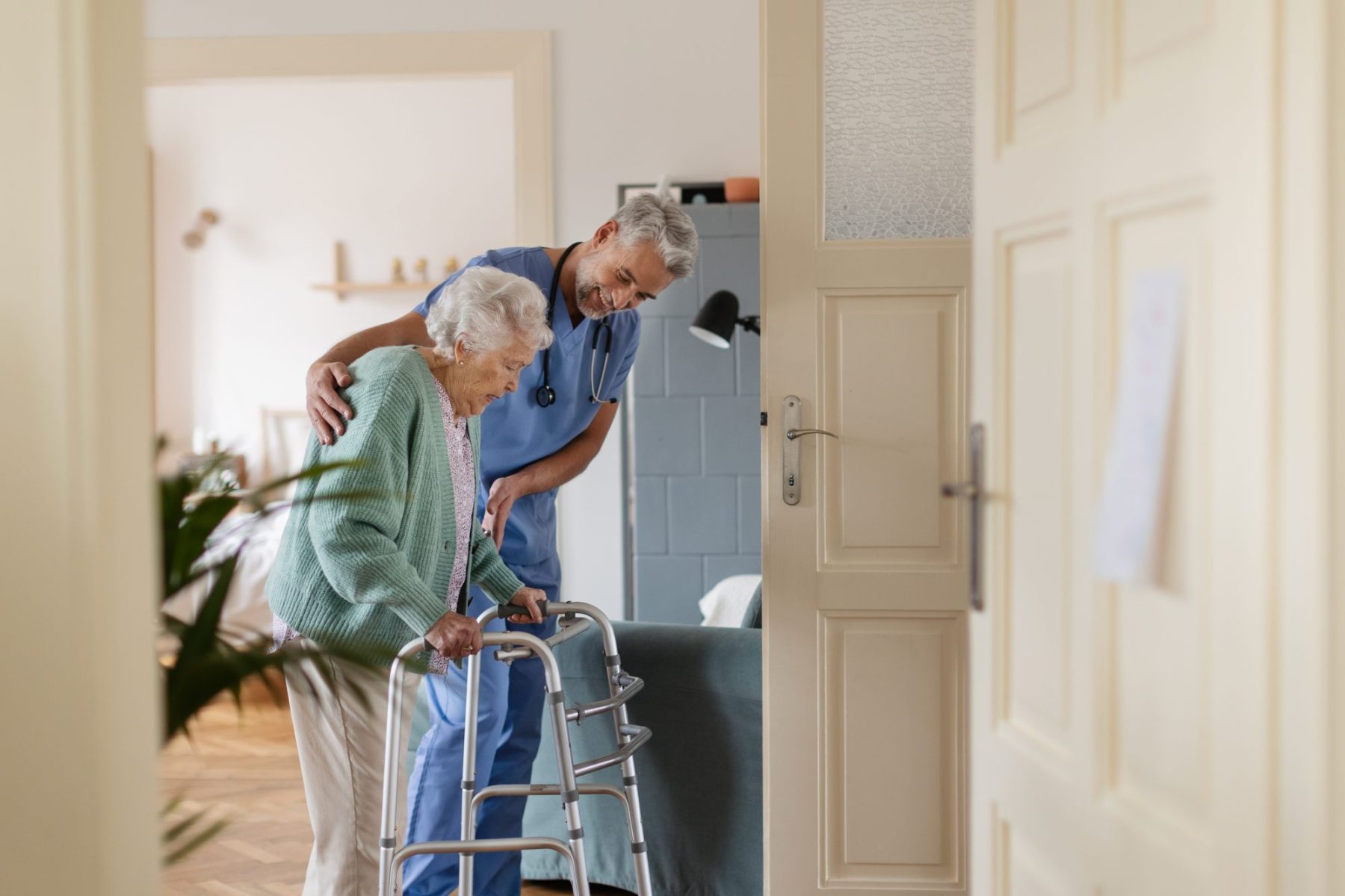 Caregiver assisting elderly resident with a walker.