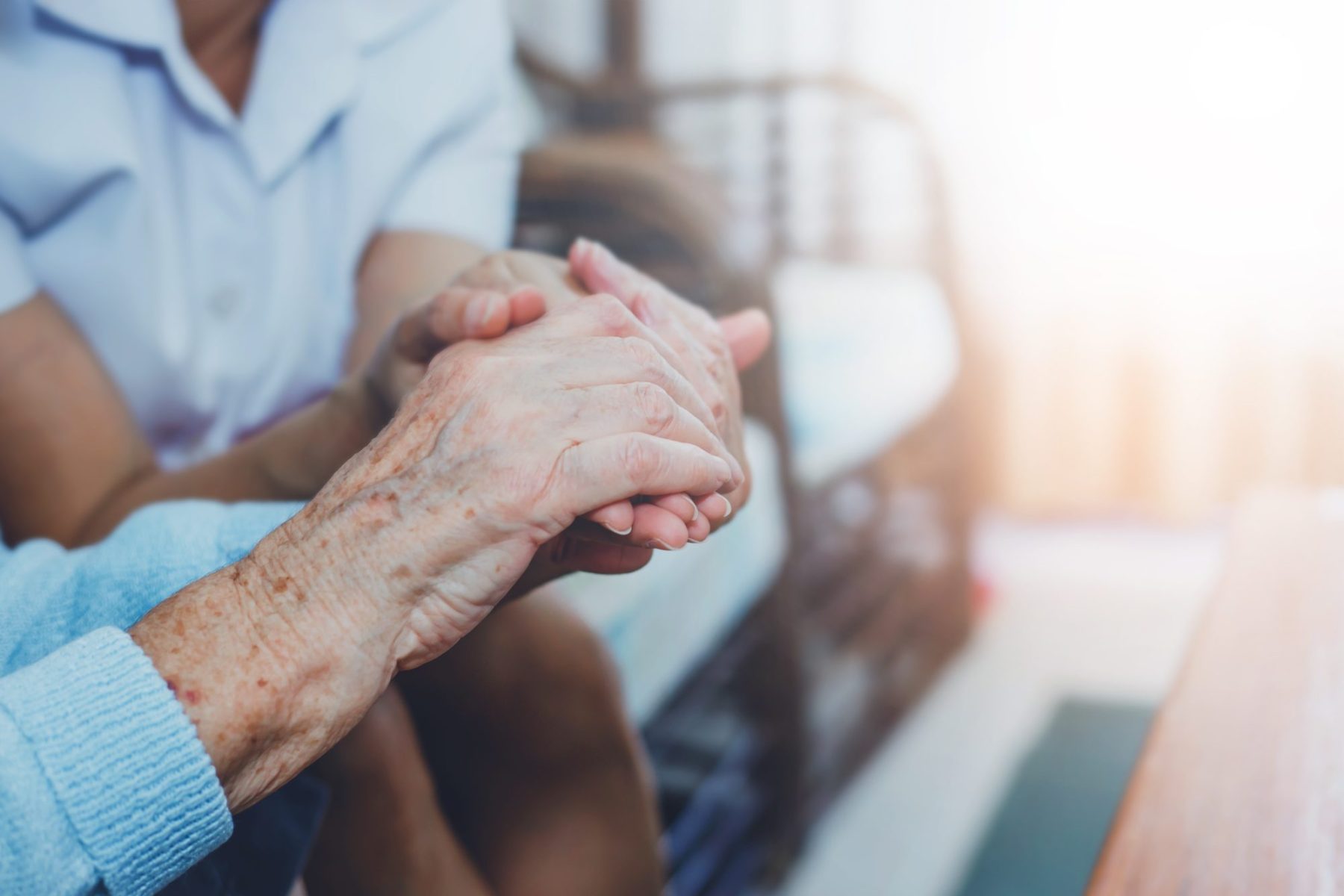 Caregiver holding a senior's hands warmly.