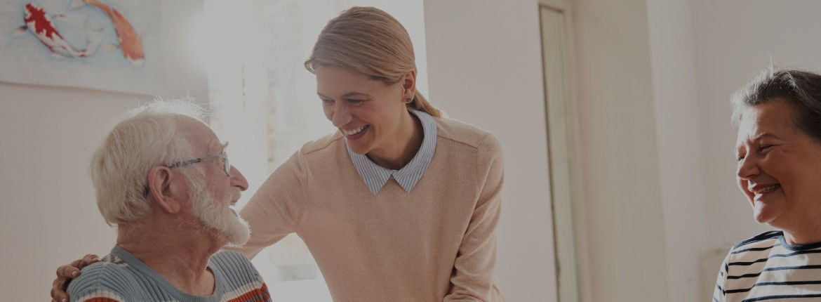 A staff member interacting with smiling residents.
