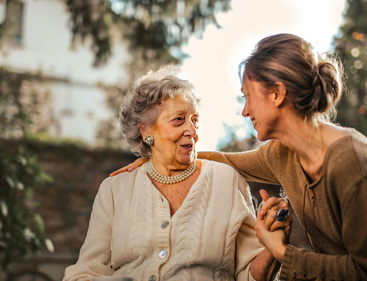 A caregiver interacting with a happy senior woman outdoors.