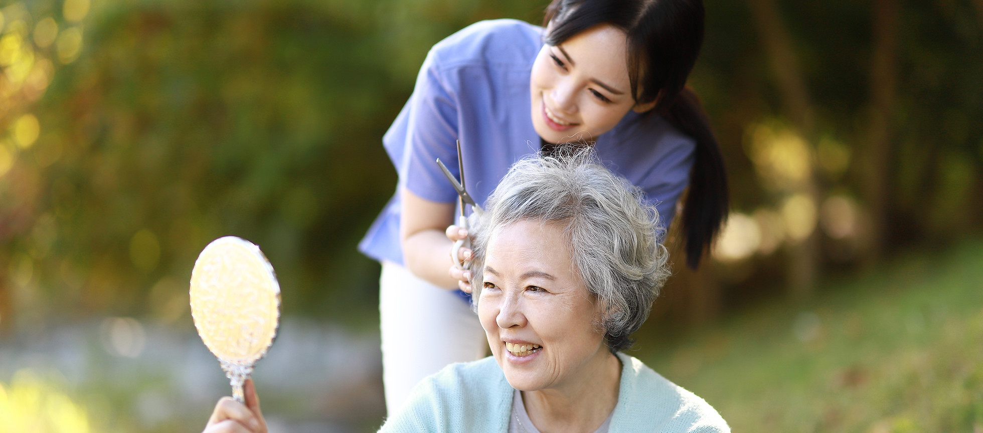 Senior woman smiling in outdoor setting with caregiver.