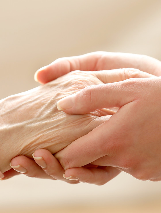 A caregiver holding an elderly person's hand.