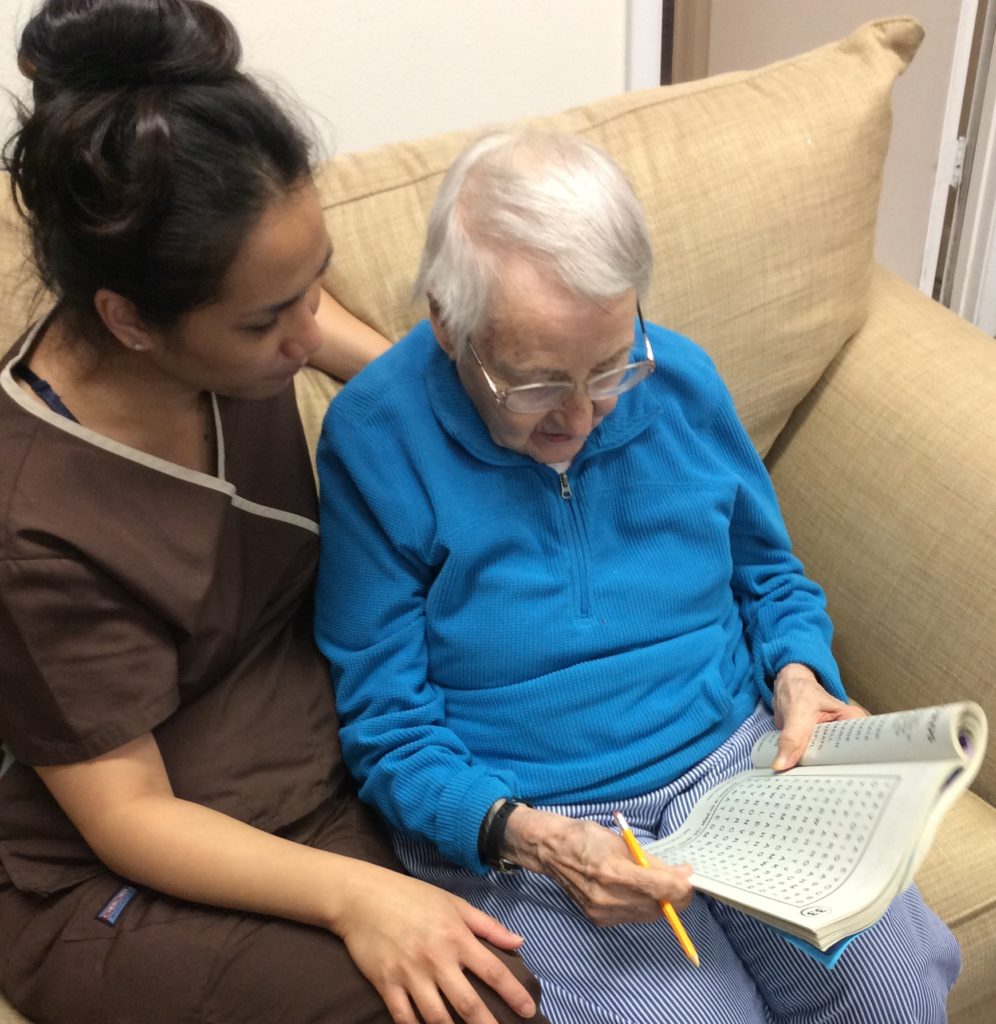 A caregiver assisting an elderly resident with a puzzle.
