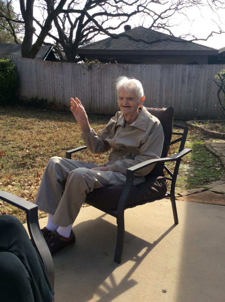 Elderly man waving while sitting outside