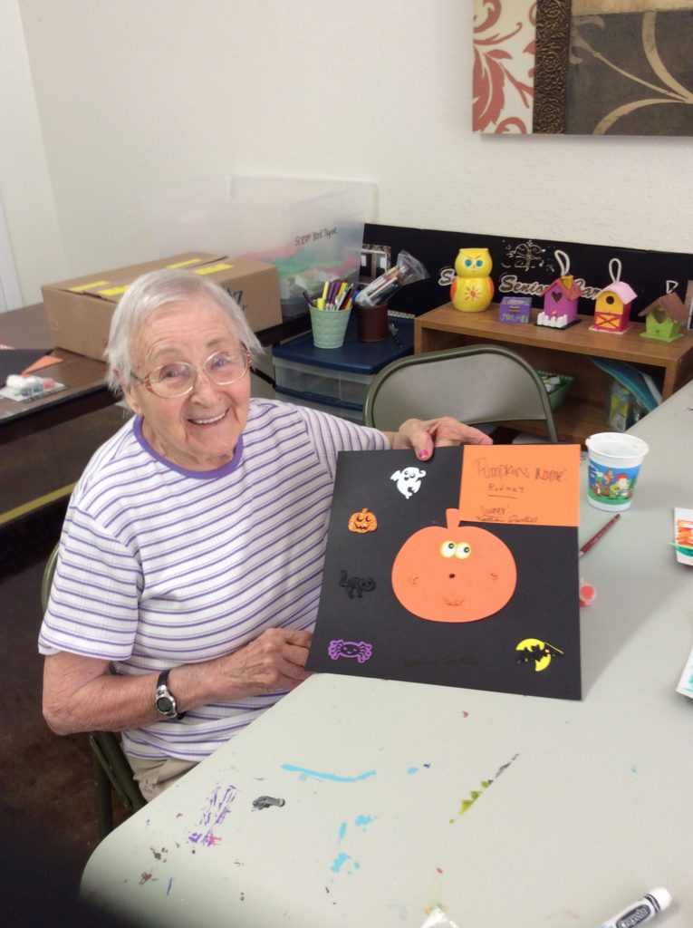 Elderly woman making crafts in activity space.