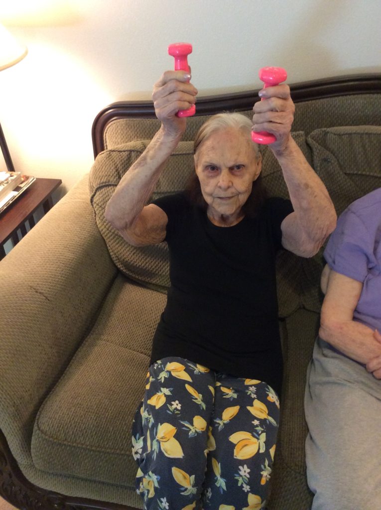 Elderly woman exercising with pink dumbbells