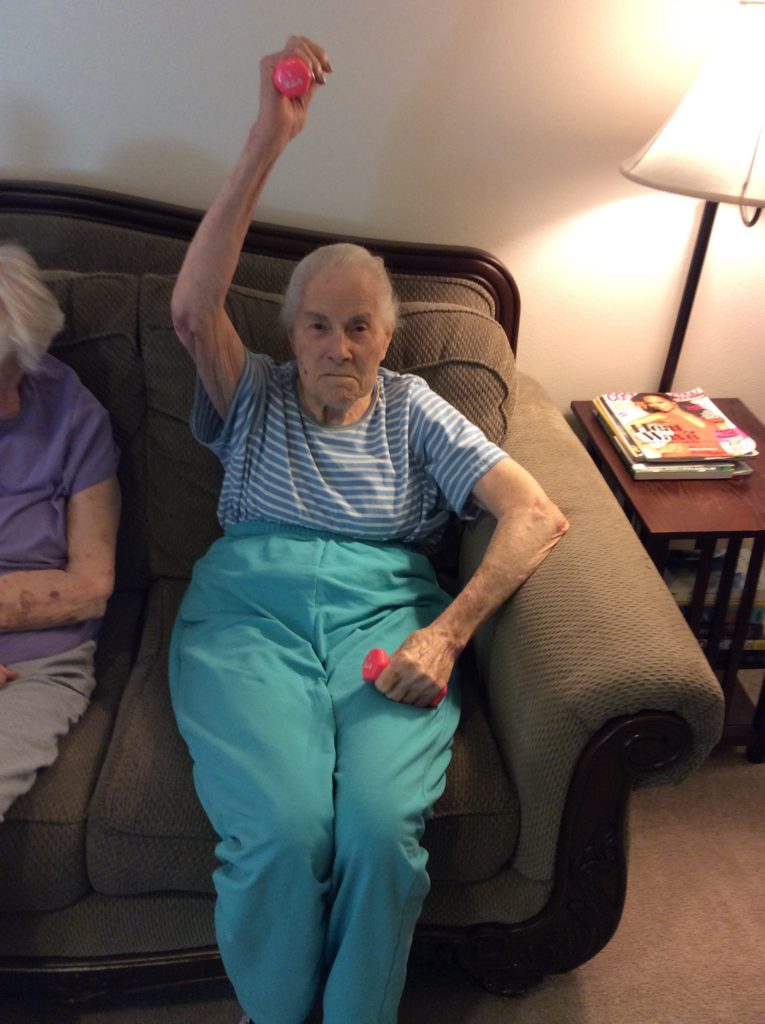 Elderly resident exercising with pink weights