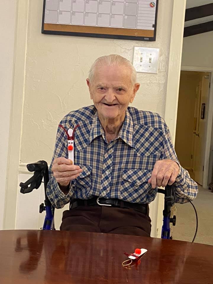 Elderly man at a table holding an object.