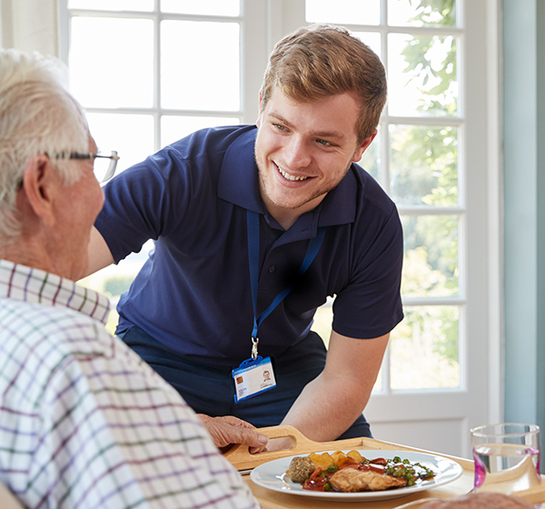 Caregiver serving food to elderly resident
