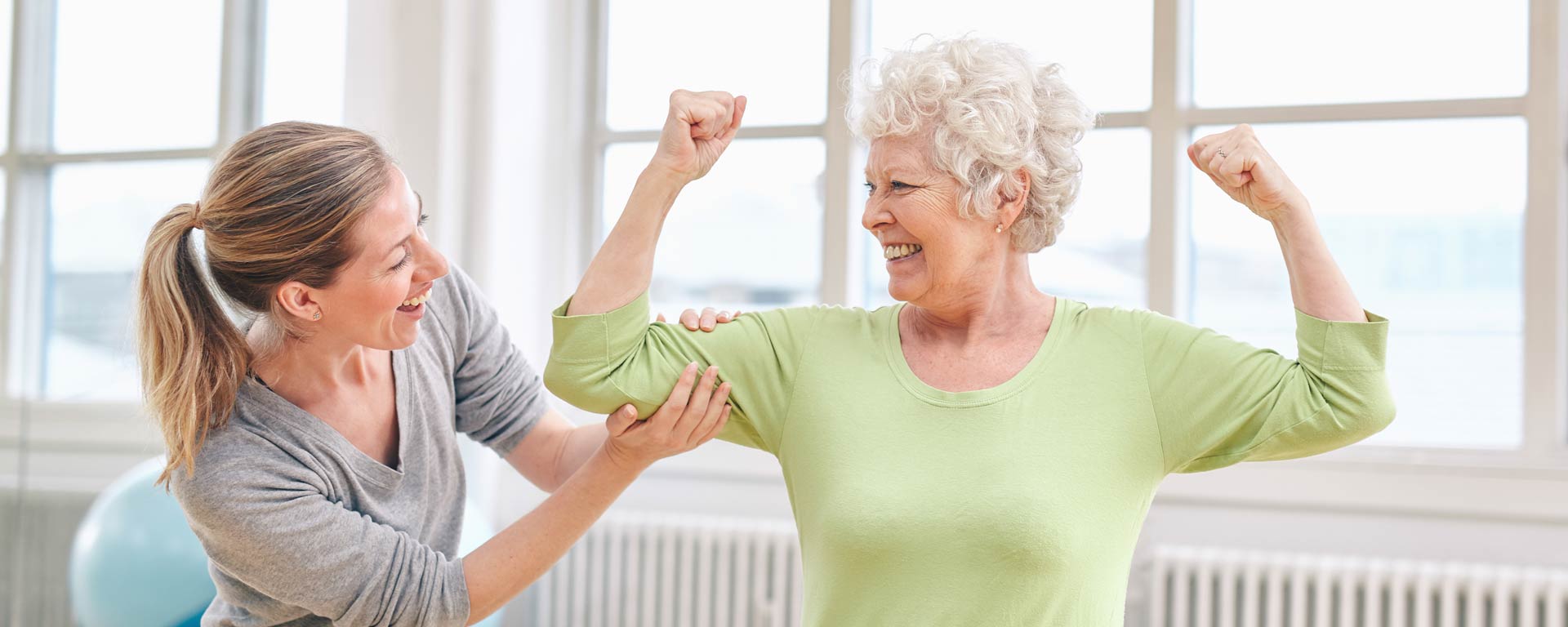 Senior woman showing strength with caregiver assistance.