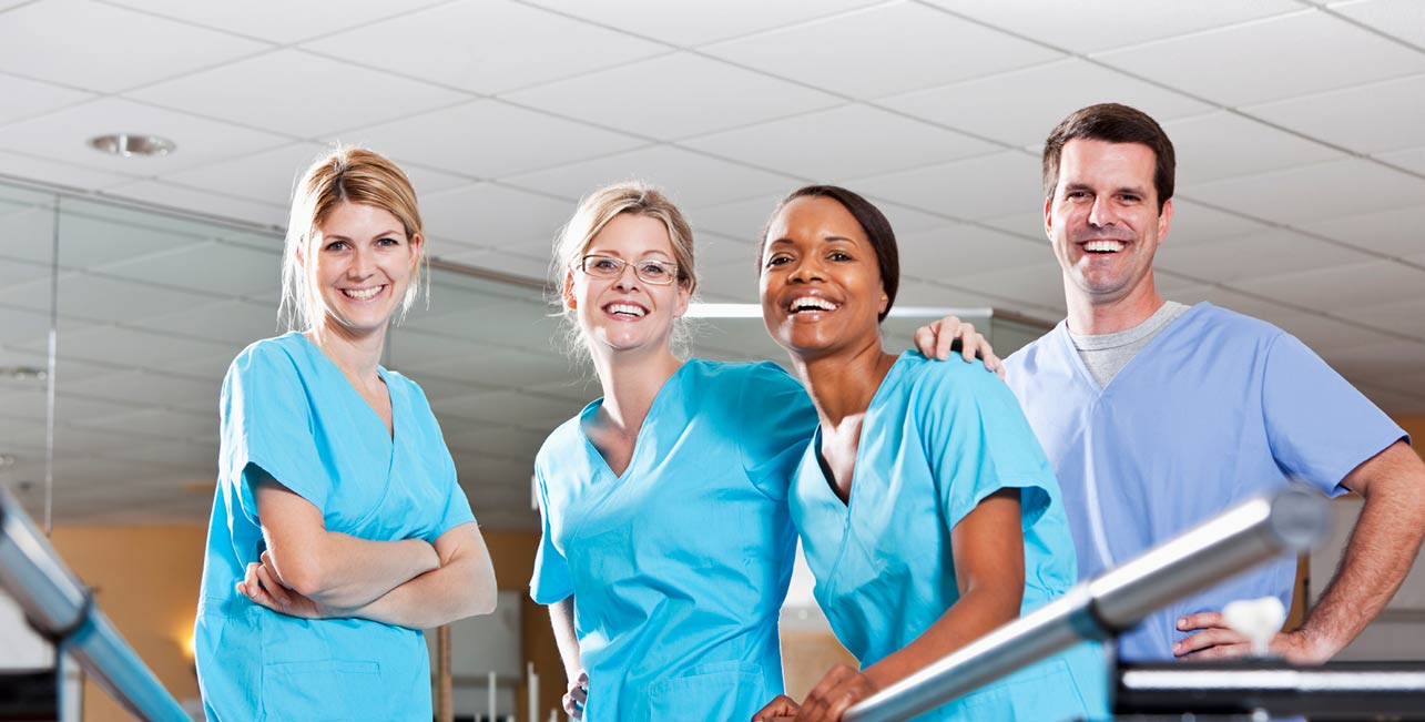 Four healthcare staff members smiling together.