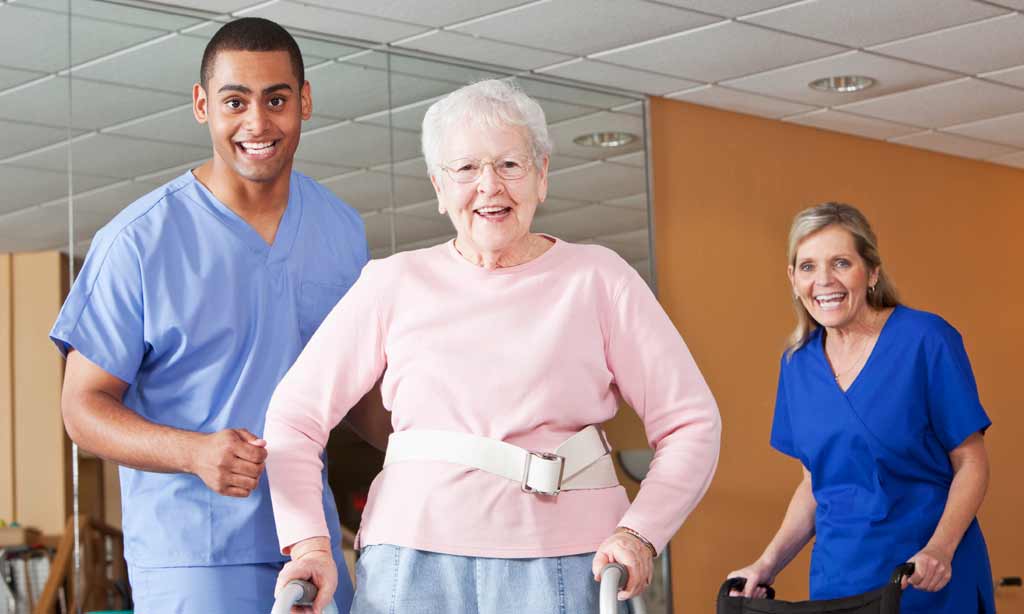 Staff assisting an elderly resident in a rehabilitation setting.
