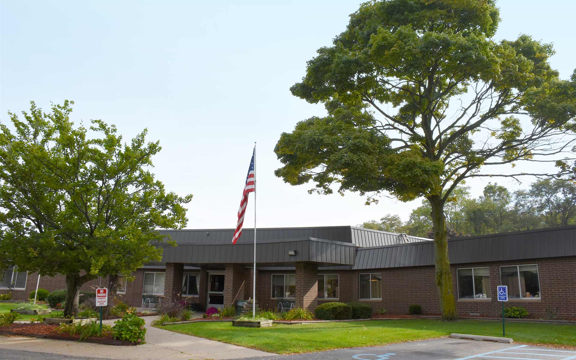 Exterior view of the facility with trees and flag.