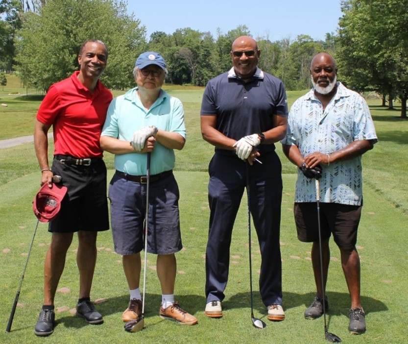 Group of four men golfing on a sunny day.