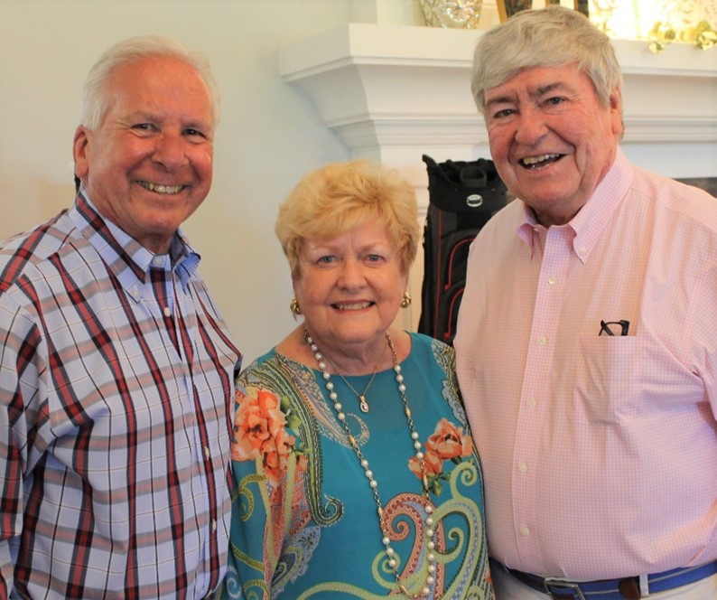 Three smiling individuals at a gathering.