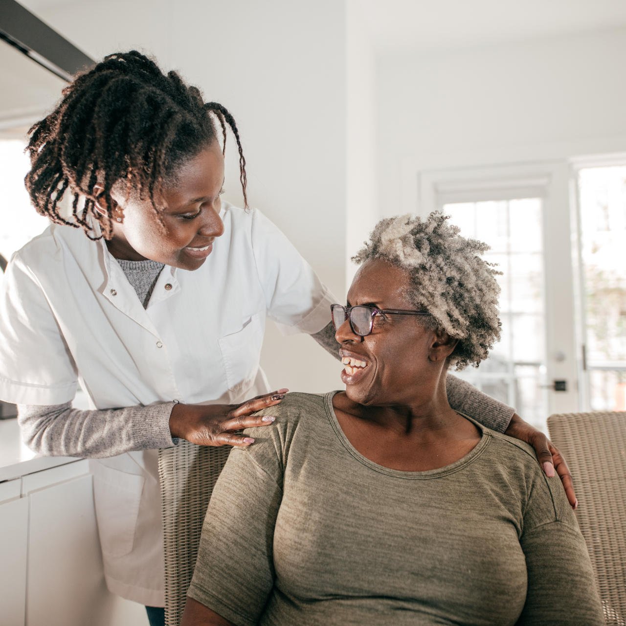 Caregiver assisting a smiling resident indoors.