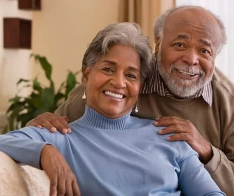 Smiling elderly couple sitting together indoors.