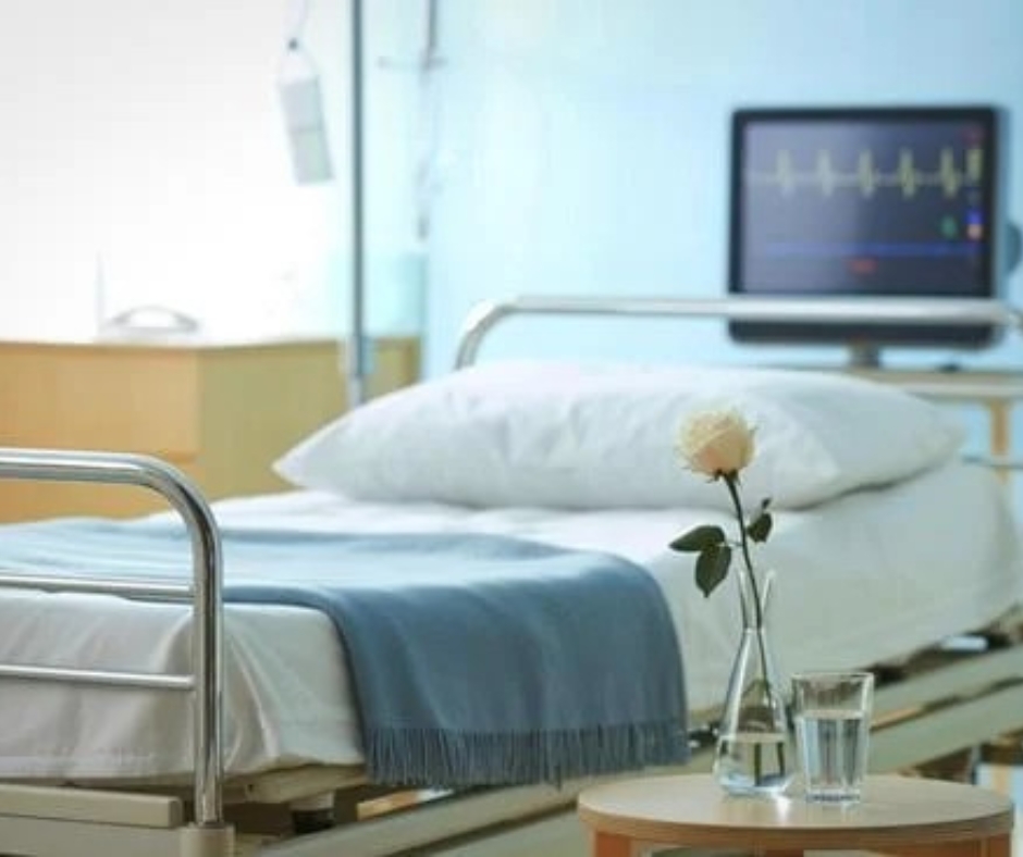 Hospital room with a bed, a flower, and a monitor.