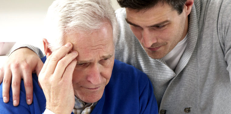 An elderly man being comforted by a younger man.