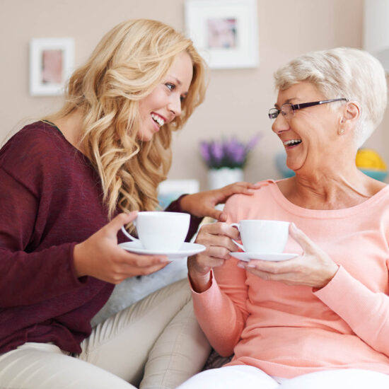 Two women enjoying tea and laughing together.