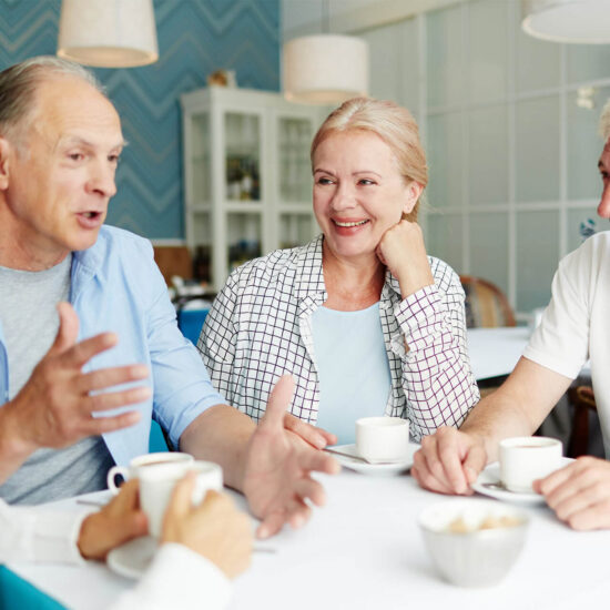 Seniors enjoying conversation over coffee in a common area.