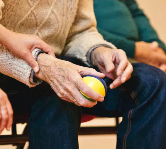 Elderly hands holding a ball during an activity.