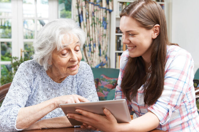 Resident and caregiver using a tablet together