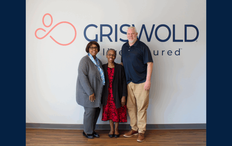 Three people standing together in front of a logo.