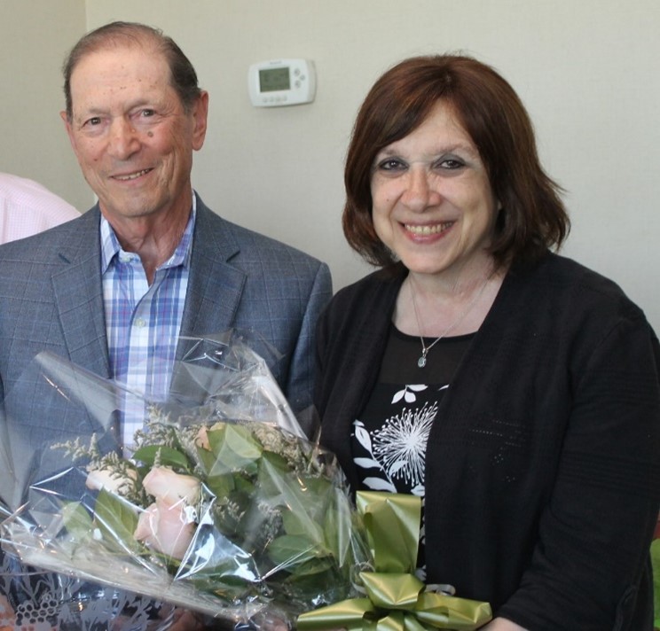 Two people posing with a bouquet of flowers.