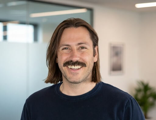 A smiling male staff member in a bright interior.