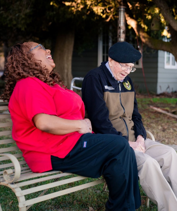 Staff member and resident laughing together outdoors