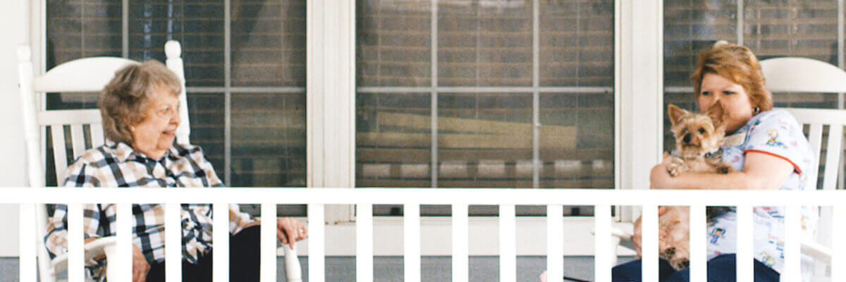 Two women on a porch with a dog.