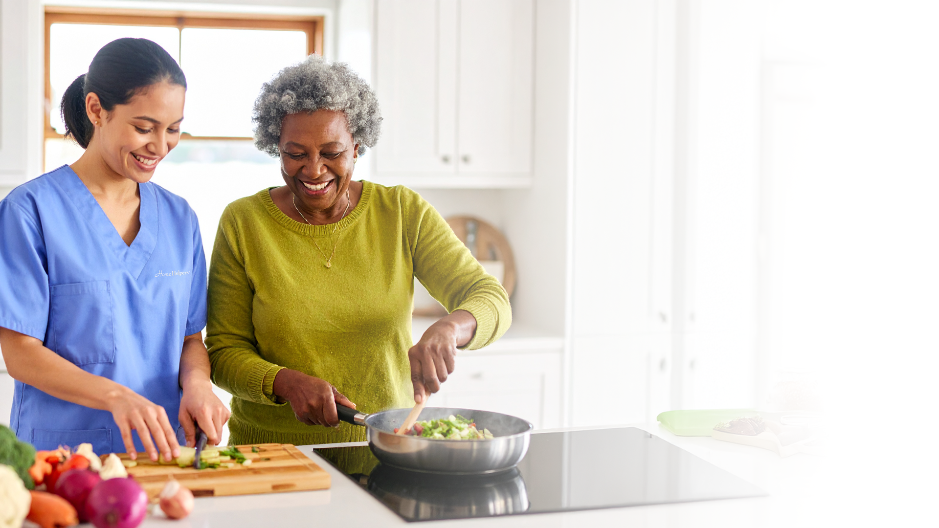 Staff and resident cooking together in a kitchen