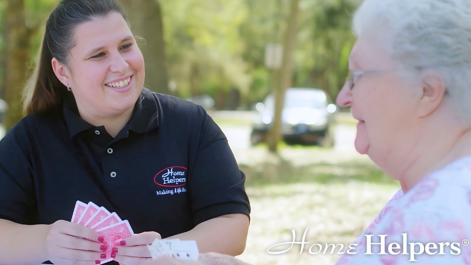 A caregiver playing cards outdoors with a senior.