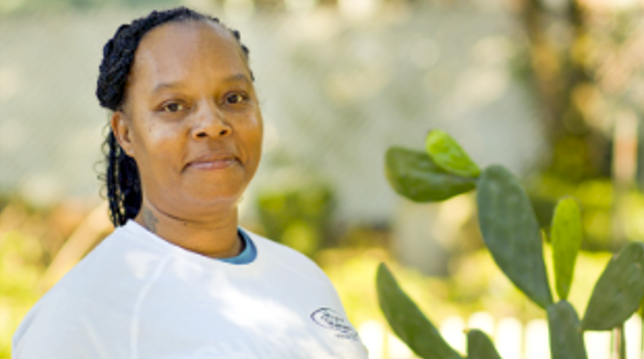 Staff member smiling in a garden setting.