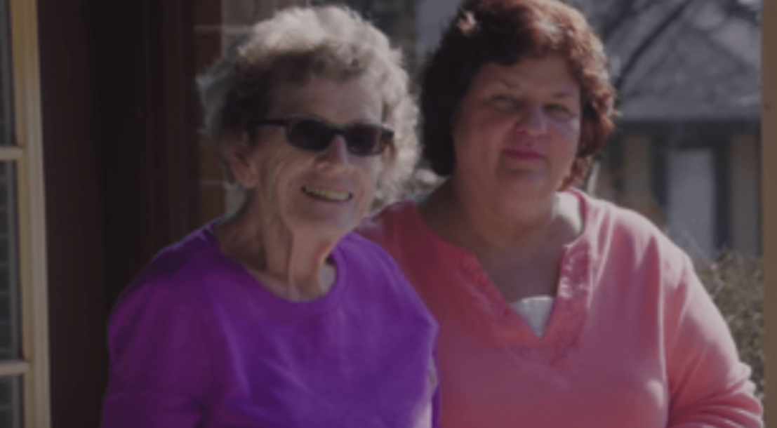 Two women smiling outdoors at a facility.