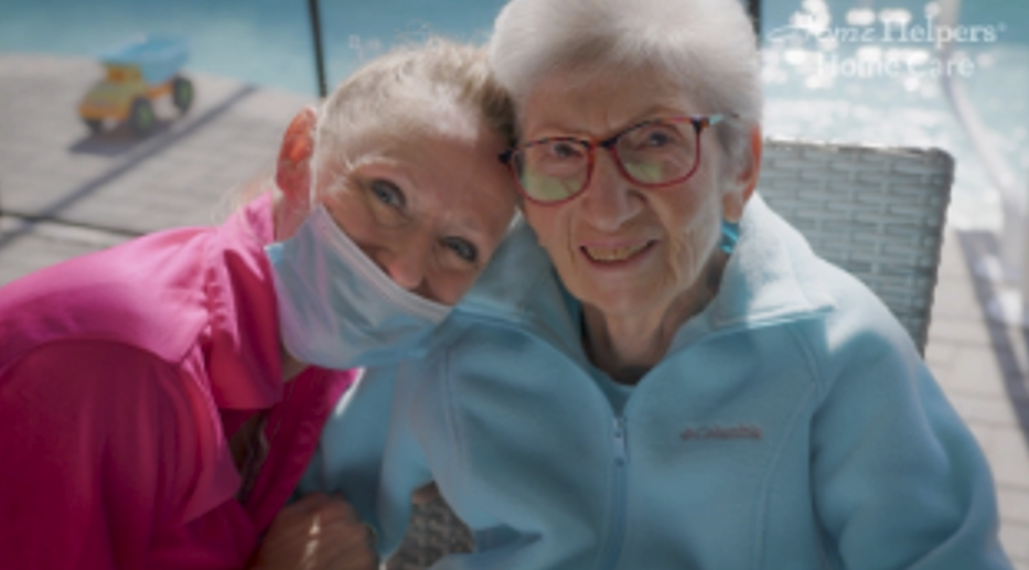 Caregiver and resident smiling outdoors together.
