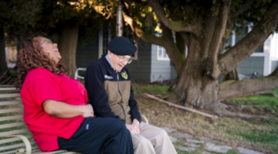 Caregiver and resident laughing together outdoors