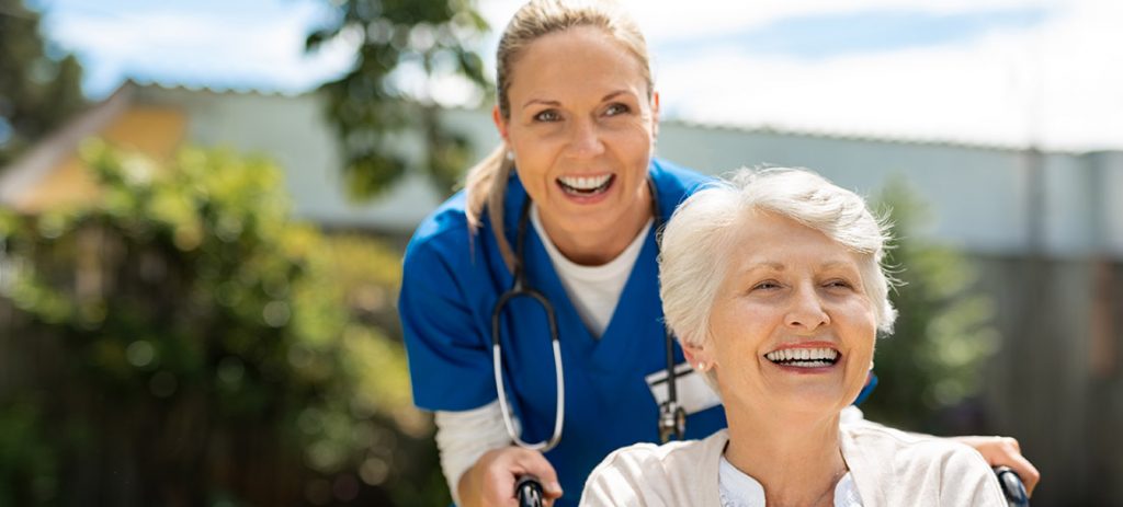 Nurse smiling with a resident in a wheelchair