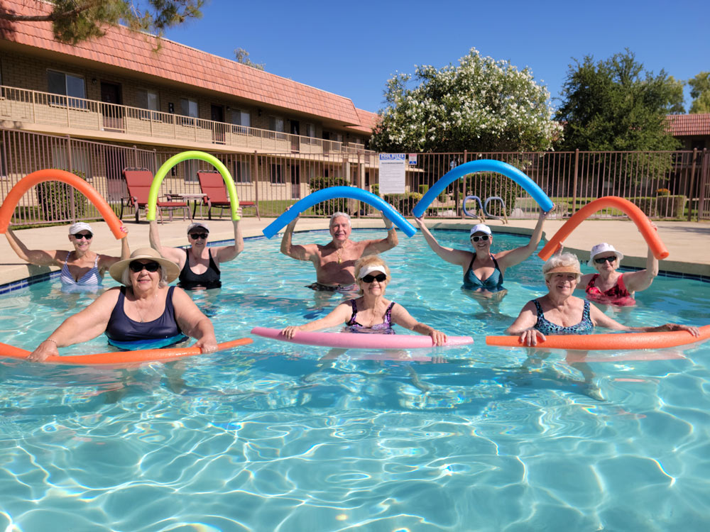 Residents enjoying water aerobics in a sunny pool
