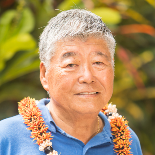 A smiling resident wearing a lei outdoors